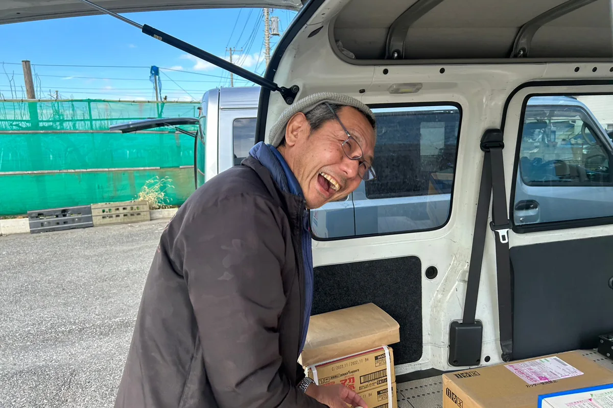 軽貨物車の荷室へ配送する荷物を積み込むドライバー